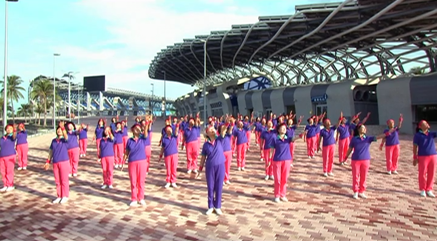 Large Praise Dance group exercising together in a sunny plaza